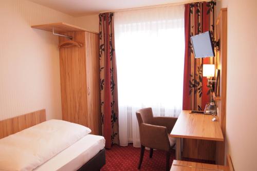 a hotel room with a bed and a desk and a window at Hotel am Bad in Tübingen
