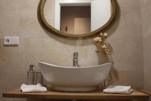 La salle de bains est pourvue d'un lavabo blanc et d'un miroir. dans l'établissement La Casa Toledana Estudio - Patio y Artesonado, à Tolède