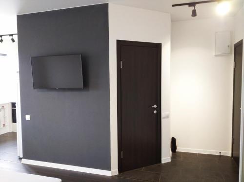 a black door with a flat screen tv on a wall at White Apartment in Poltava