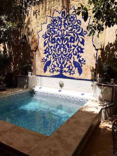 a swimming pool with a blue and white stenciled wall at Les Bains de Fez Tara in Fès