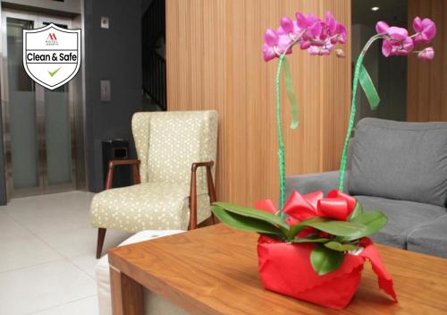 a table with a red vase with flowers on it at M Hotel in Jakarta