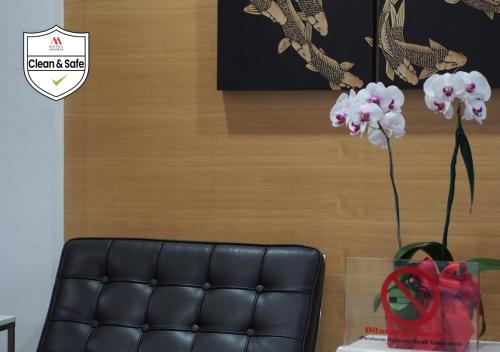 a black leather couch with a vase of flowers on a table at M Hotel in Jakarta