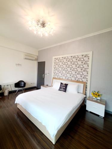 a bedroom with a large white bed and a chandelier at Beautiful Homestay in Suao