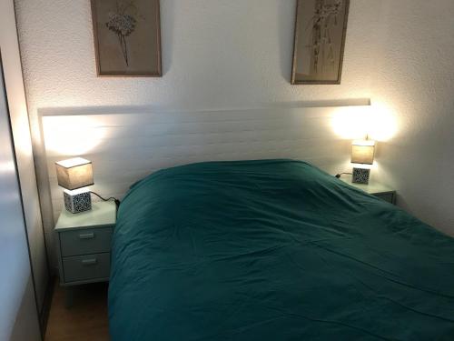 a bedroom with a green bed and two lamps at Capbreton Notre-Dame in Capbreton