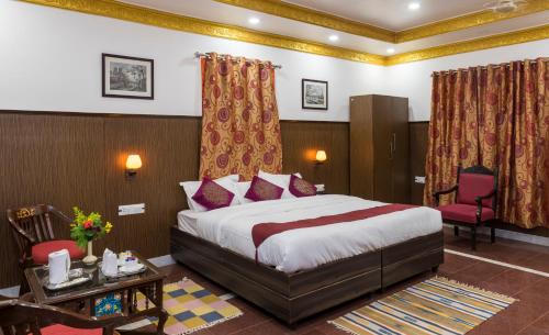 Habitación de hotel con cama, mesa y sillas en Hotel Harmony, en Khajurāho