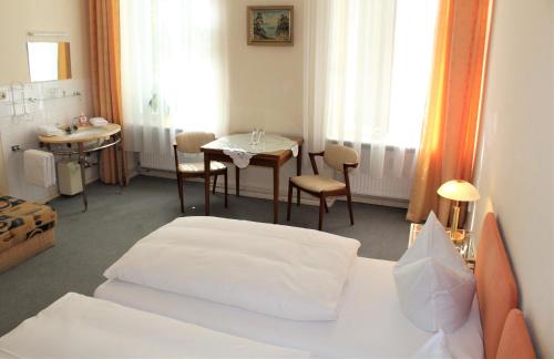 Habitación de hotel con cama y mesa con sillas en Pension Brinn, en Berlín