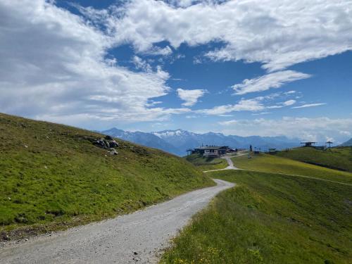 a dirt road on a hill with mountains in the background at Penthaus Kitzebüheler Alpen in Neukirchen am Großvenediger