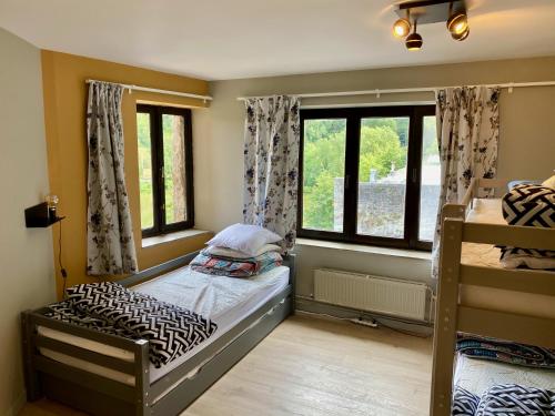 a bedroom with two bunk beds and two windows at Châtelet de Barbençon in Barbençon