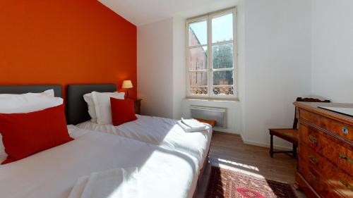 une chambre avec deux lits et un mur orange dans l'établissement Chez Gasti, à Colmar