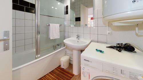 une salle de bain blanche avec un lavabo et une douche dans l'établissement Chez Gasti, à Colmar
