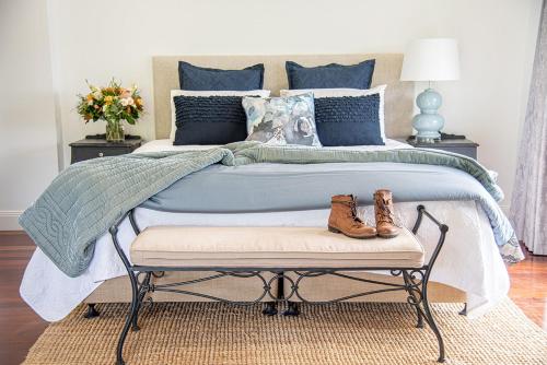 a bedroom with a large bed with two shoes on a bench at Country Mile Escape in Canungra