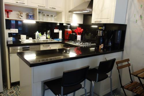 a kitchen with black and white counter tops and stools at Tilas - Rooms in 19th Century Wooden Townhouse,Kadikoy in Istanbul