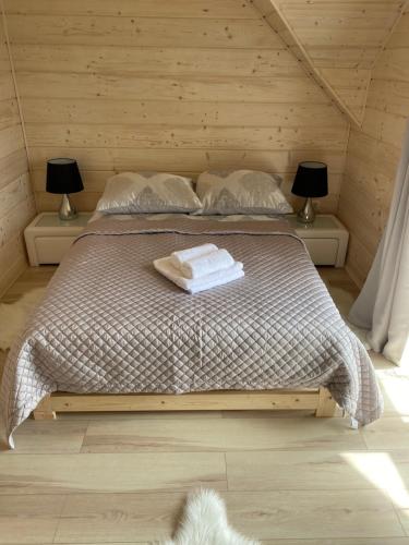 a bedroom with a bed with two lamps and towels at Bieszczadzkie Chaty in Polańczyk