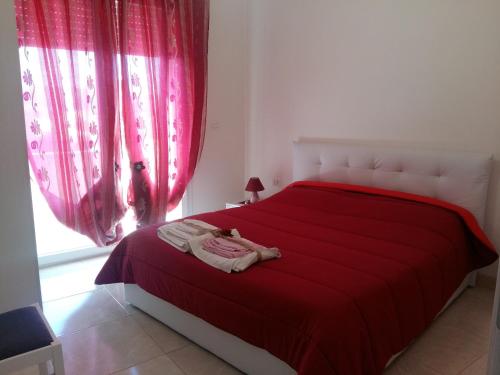 タヴィアーノにあるAppartamento Pompeaの赤いベッド1台(赤いシーツ付)、窓が備わります。