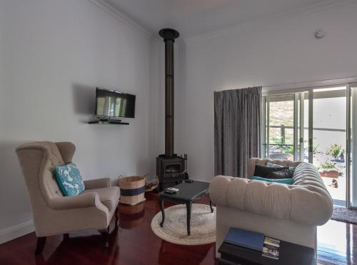 a living room with two chairs and a stove at Country Mile Escape in Canungra