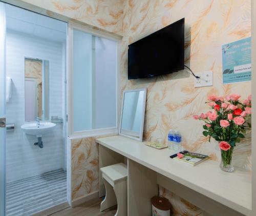 baño con lavabo y TV en la pared en Nắng Chiều Central Hotel en Da Lat