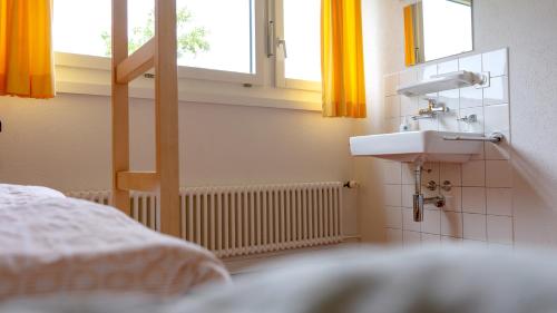 uma casa de banho com um lavatório e uma janela com cortinas amarelas em St. Gallen Youth Hostel em St. Gallen