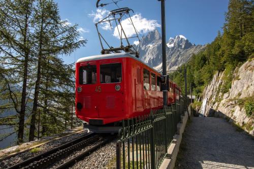 a red train traveling down the tracks in the mountains at Refuge du Montenvers in Chamonix-Mont-Blanc