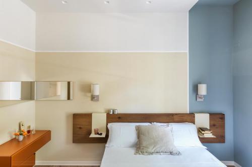 a bedroom with a white bed with a wooden headboard at San Leonardo Suites in Verona