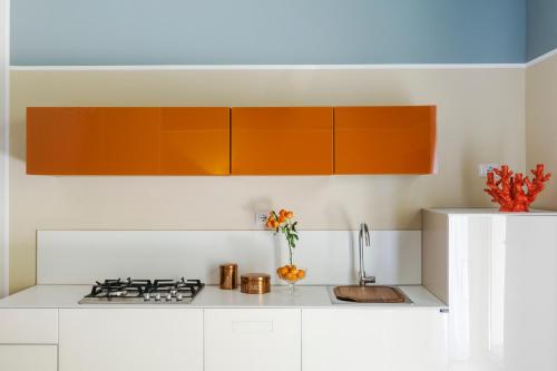 a kitchen with white counters and orange cabinets at San Leonardo Suites in Verona