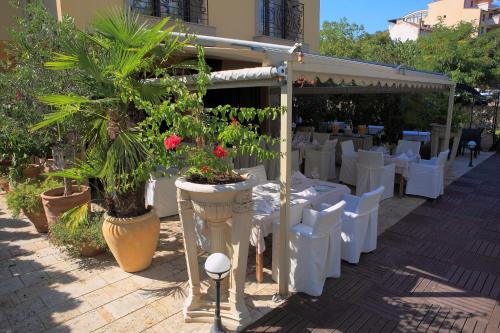a restaurant with white tables and chairs and plants at Park Hotel Sandanski in Sandanski