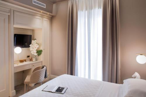a bedroom with a bed and a desk and a window at Hotel Savoia in Alassio