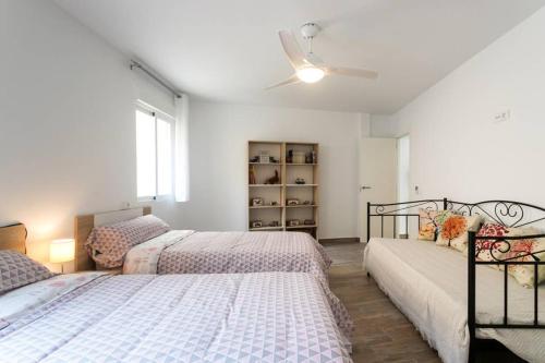ein Schlafzimmer mit zwei Betten und einem Deckenventilator in der Unterkunft Espacioso y céntrico piso con zona chill-out in Alicante