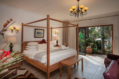a bedroom with a canopy bed and a patio at Tamboti Lodge Guest House in Tzaneen