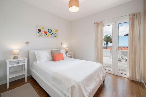 - une chambre blanche avec un lit et une grande fenêtre dans l'établissement Terrace Vila by An Island Apart, à Caniço