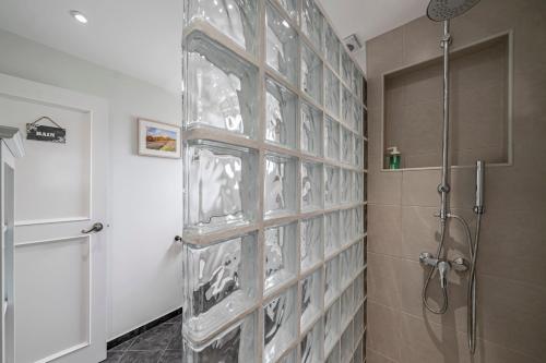 a glass block wall in a bathroom with a shower at Terrace Vila by An Island Apart in Caniço