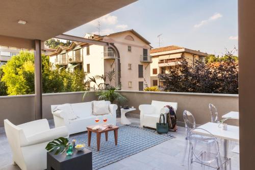 un patio con sillas blancas y mesas en un balcón en San Leonardo Suites en Verona