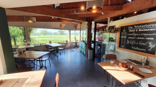 een restaurant met tafels en stoelen en een schoolbord aan de muur bij Hotel de Watertoren in Dordrecht