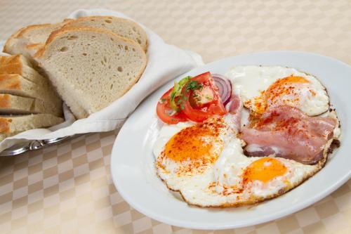 un plato de comida con huevos y pan en una mesa en Panoráma Panzió, en Tatabánya