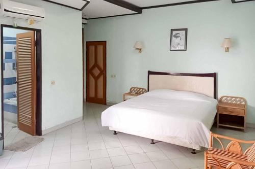 a bedroom with a white bed and two chairs at RedDoorz Plus near Tugu Mercusuar Anyer in Serang