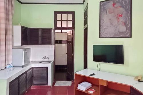 a living room with a television and a kitchen at RedDoorz Plus near Tugu Mercusuar Anyer in Serang