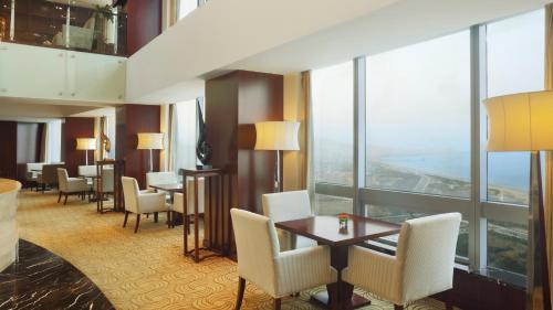a hotel room with a table and chairs and windows at Crowne Plaza Yantai Sea View by IHG in Yantai