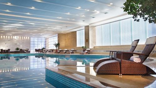 a pool in a hotel with chairs and a pool at Crowne Plaza Yantai Sea View by IHG in Yantai