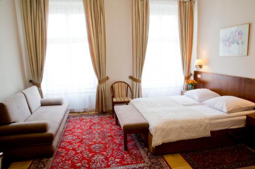 1 dormitorio con cama, sofá y ventanas en Hotel Polonia en Cracovia