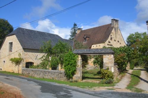 an old stone house with an archway on a street at L'ère du temps in Cuzance