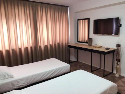 a room with two beds and a desk with a television at Hotel Lido in Durrës