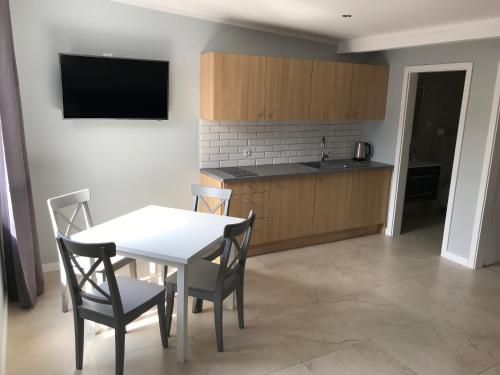 a kitchen and dining room with a white table and chairs at Apartamenty i Domki WyDmy Międzywodzie in Międzywodzie
