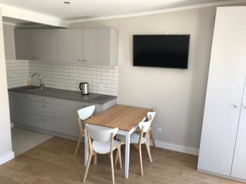 a kitchen with a wooden table and white chairs at Apartamenty i Domki WyDmy Międzywodzie in Międzywodzie