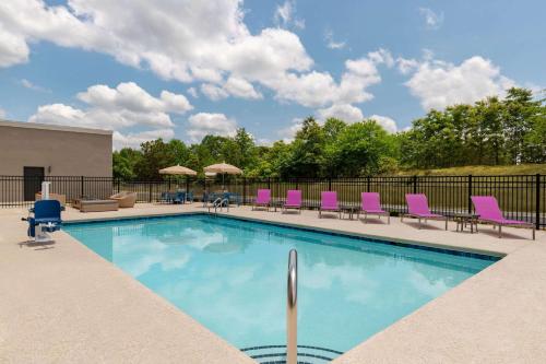 a swimming pool with pink chairs and chairs at La Quinta Inn & Suites by Wyndham Braselton in Braselton