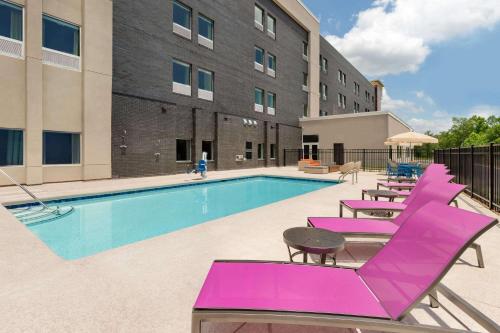 a swimming pool with purple lounge chairs next to a building at La Quinta Inn & Suites by Wyndham Braselton in Braselton