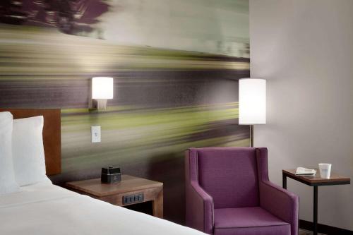 a bed and a purple chair in a hotel room at La Quinta Inn & Suites by Wyndham Braselton in Braselton