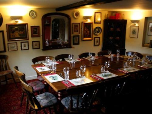uma sala de jantar com uma longa mesa de madeira e cadeiras em Golden Ball Hotel em Cambridge