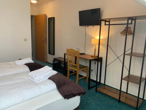 a hotel room with two beds and a desk and a television at Hotel Rosengarten in Frankfurt/Oder