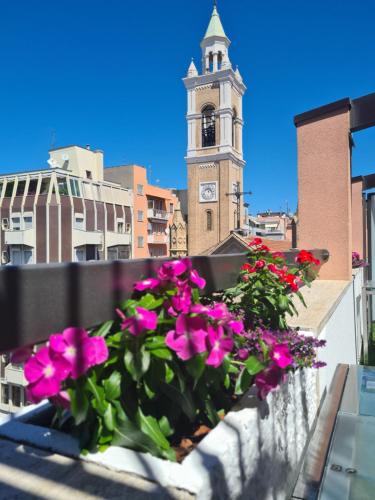 a window box with flowers on a balcony with a clock tower at Terrazze Caracciolo in Pescara
