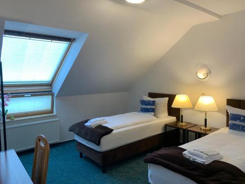 a attic room with two beds and a window at Hotel Rosengarten in Frankfurt/Oder
