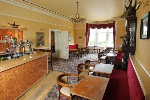 a restaurant with tables and chairs and a bar at Cressfield Country House Hotel in Ecclefechan